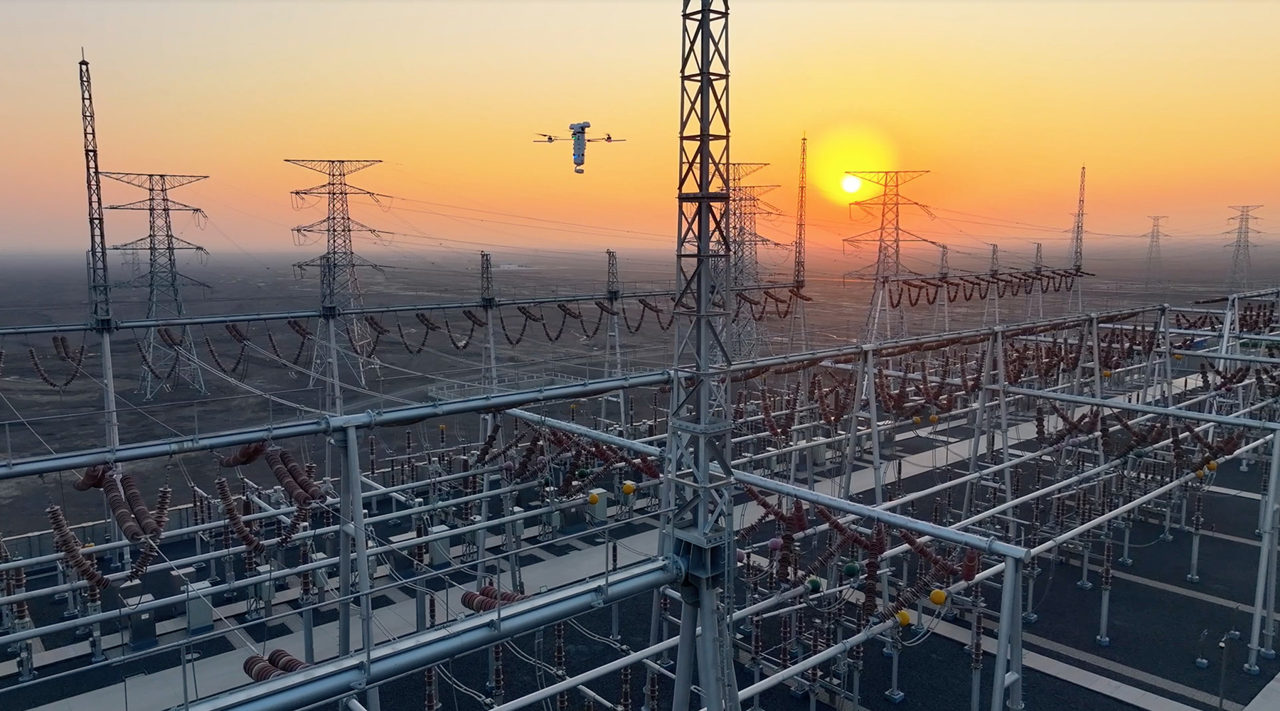 Drone inspecting power infrastructure at sunset